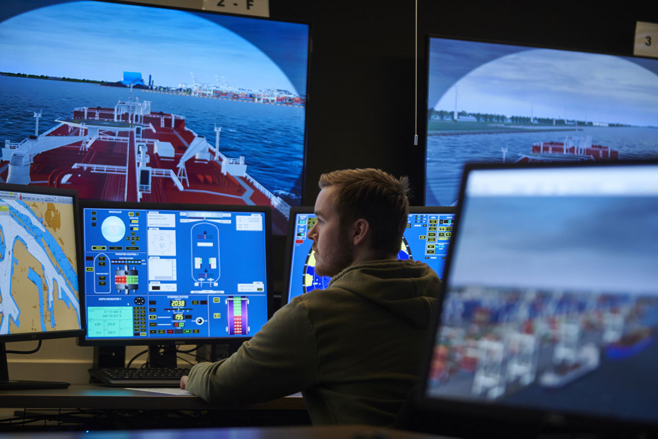 Student foran store skjermar i ein skipssimulator