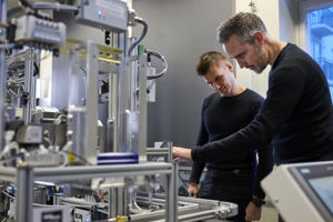 Bilde av to studenter som held på med teknisk utstyr i ein lab.