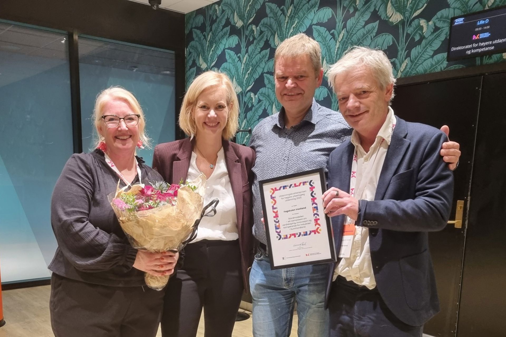 Bildet viser fire smilande mennesker som held opp diplomet til utdanningskvalitetsprisen.