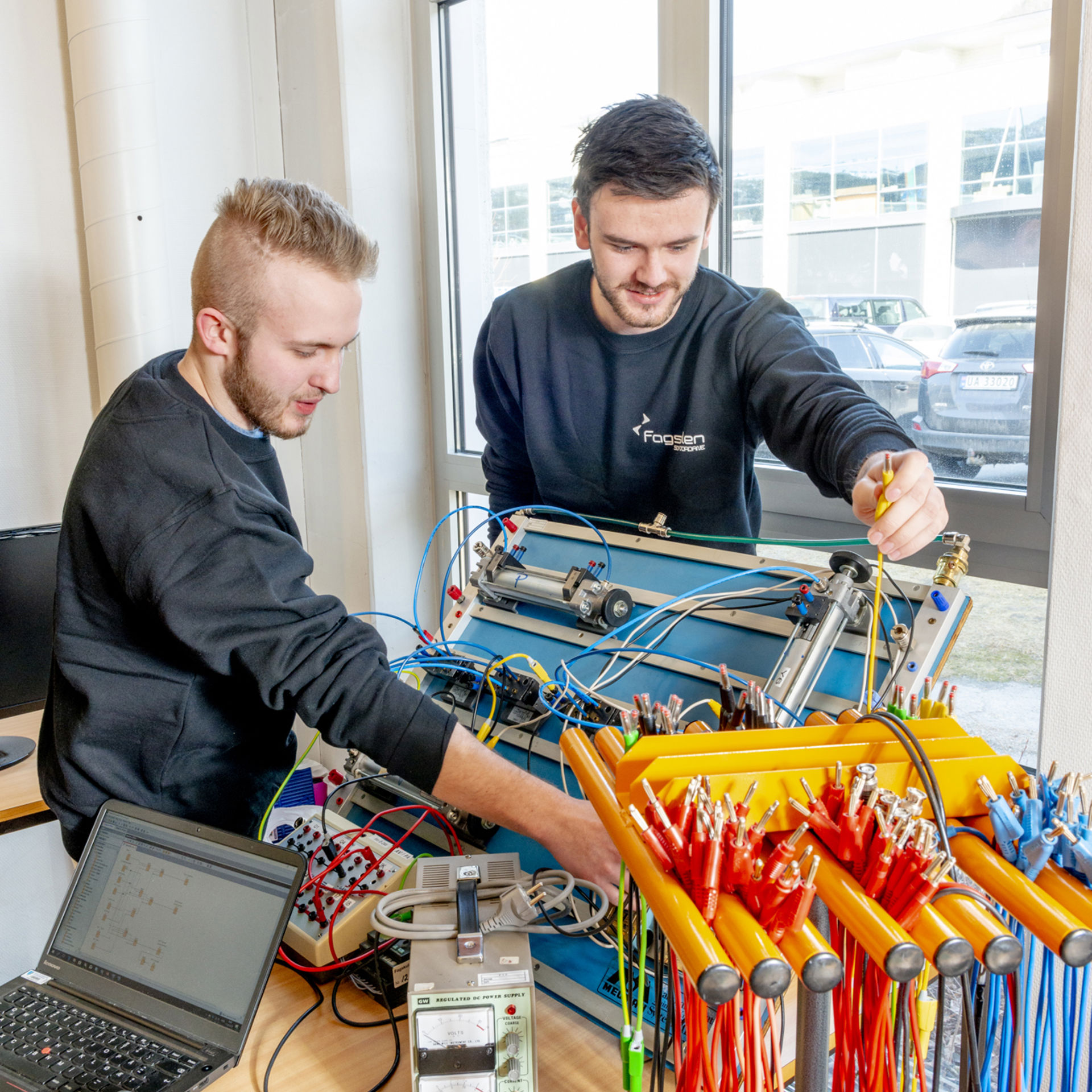 Bildet viser to studentar som koplar leidningar