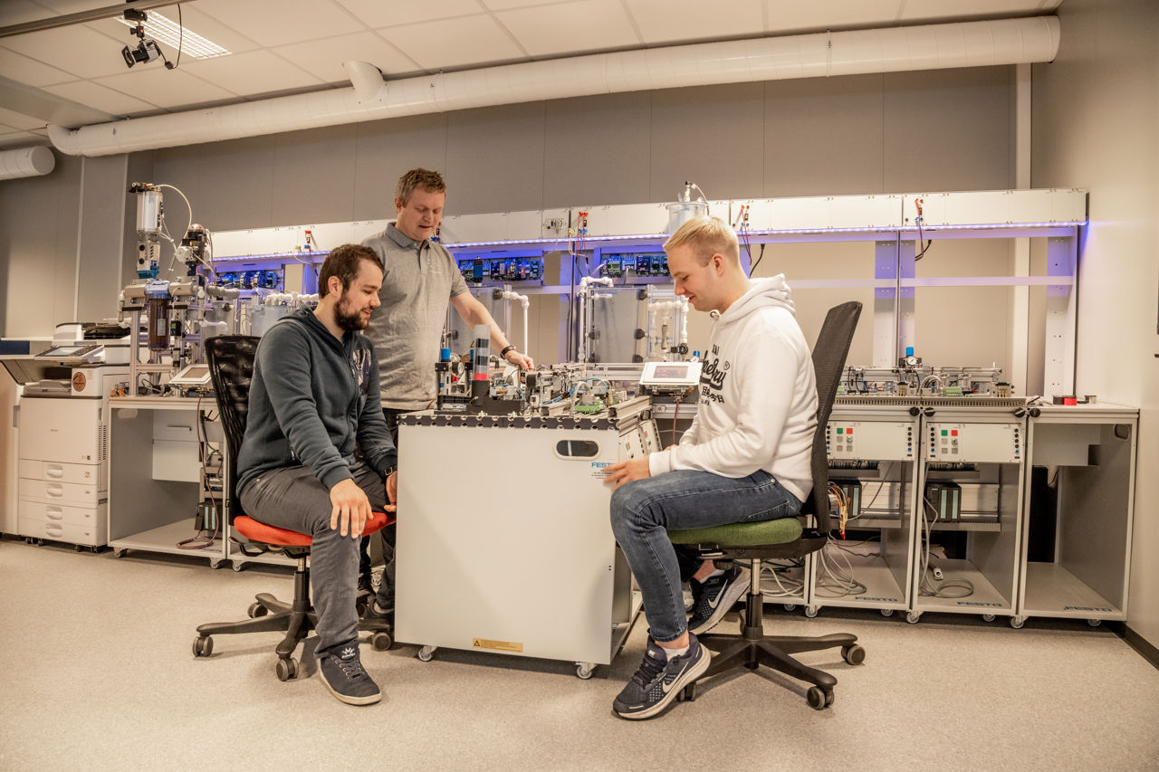 Studentar med eit automatisert teknisk anlegg på lab i Førde.